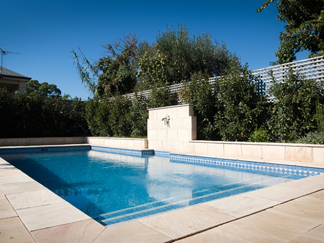 elegant custom pool design with stone pavers with upright fountain