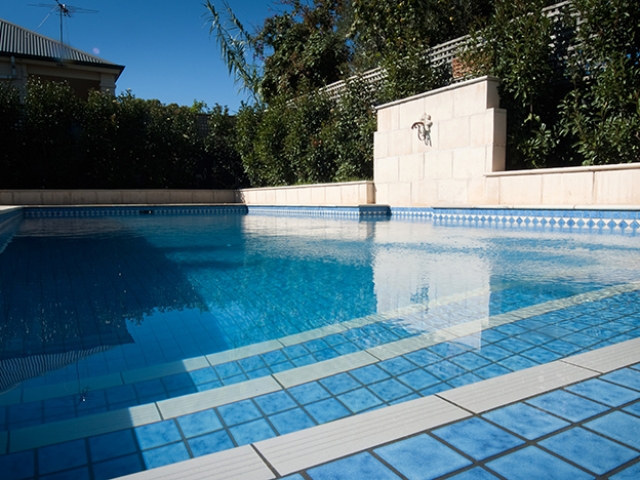 custom pool design with water feature with landscape surrounding